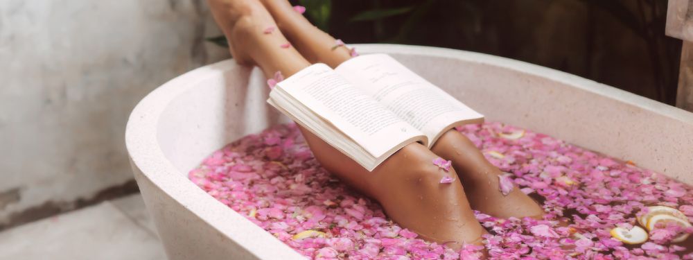 woman relaxing in tub reading a steamy romance novel - luxury and self care vibes